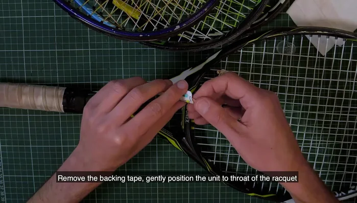 Remove the backing tape and gently position the unit on the racket throat. Apply pressure for at least 30 seconds.