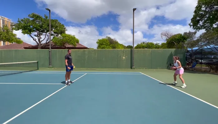 The coach throws a ball from the service line intersection.