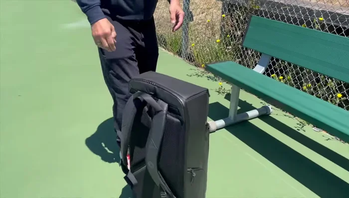 Demonstrating the straps and the bag's ability to be attached to fences.