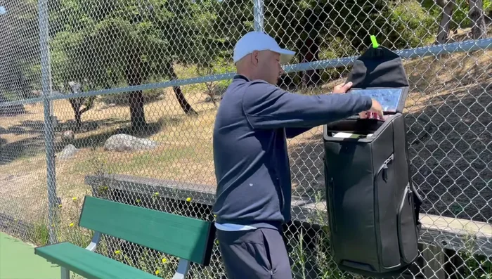 Demonstrating the straps and the bag's ability to be attached to fences.