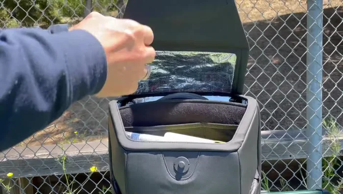 Demonstrating the straps and the bag's ability to be attached to fences.