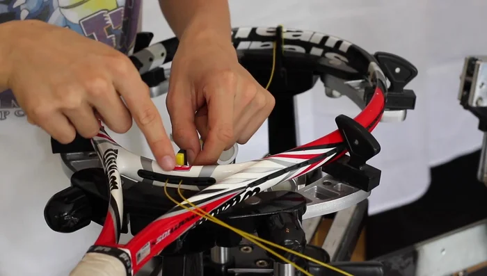 Create the first loop by threading the string back through the adjacent grommet on the opposite side, pulling it up through the center.