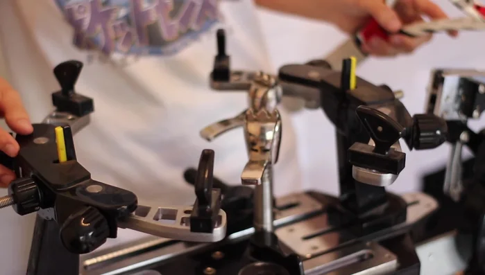 Mount the racket securely onto the stringing machine, ensuring the center is correctly aligned.