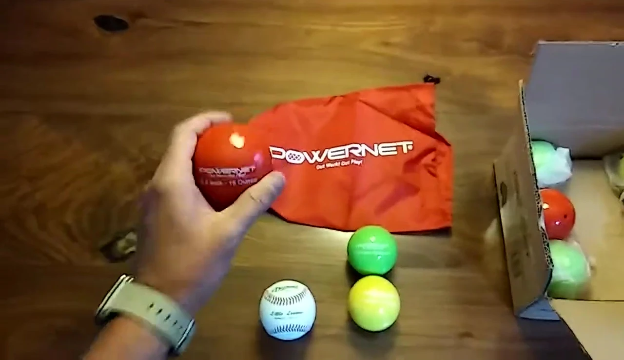 The coach squeezing one of the weighted hitting balls to highlight the dense, sand-like filling.
