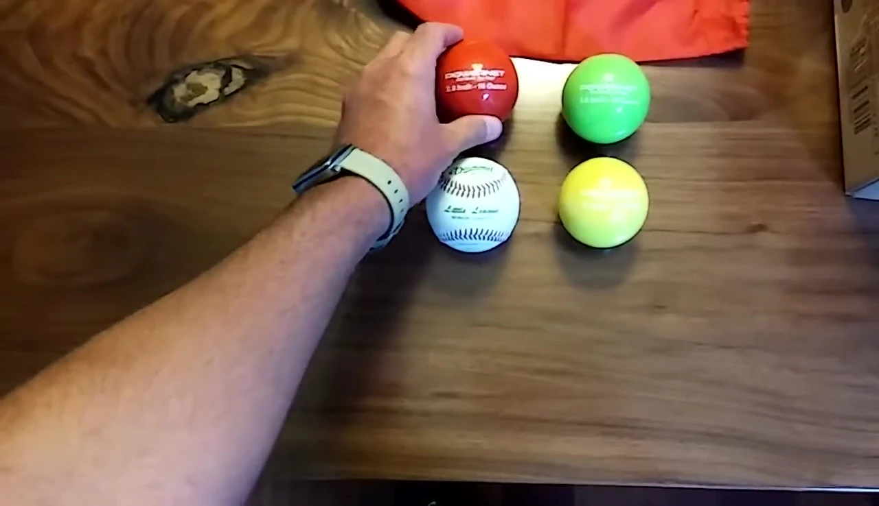 The coach demonstrating the different weight options (12, 14, and 16 ounces) and their use in soft-toss training.