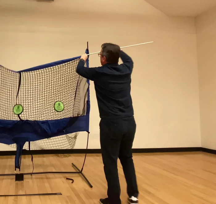 Insert the white fiberglass cross pole through the top sleeves, attaching the metal corner pieces to both the white and black poles.