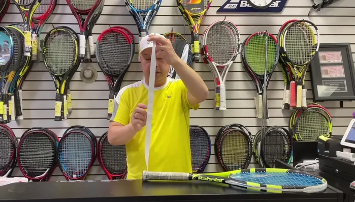 Remove the finishing tape from the overgrip, setting it aside.